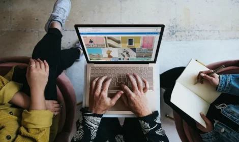 hands on keyboard of laptop with other people collaborating