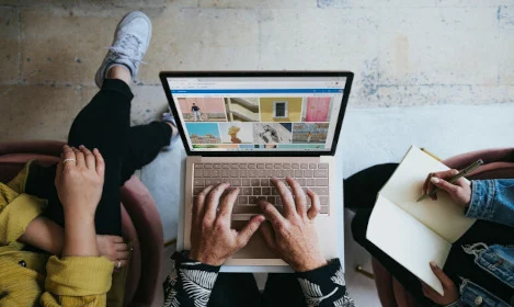 hands on keyboard of laptop with other people collaborating