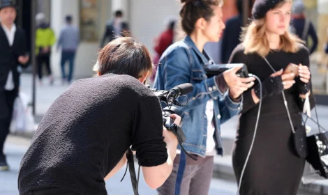 young man with camera filming 2 media ladies