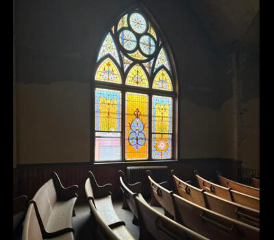 church interior and pews lit by stained glass window